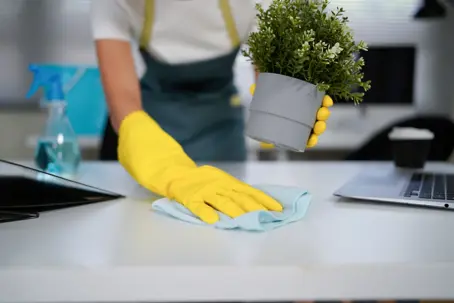 Wiping a desk with a cloth.
